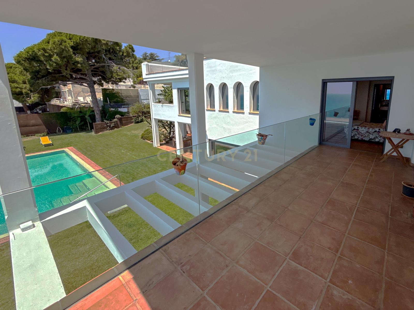 Panoramic view from Villa Can Bonita's upper terrace over garden, infinity pool and Costa Barcelona coastline.