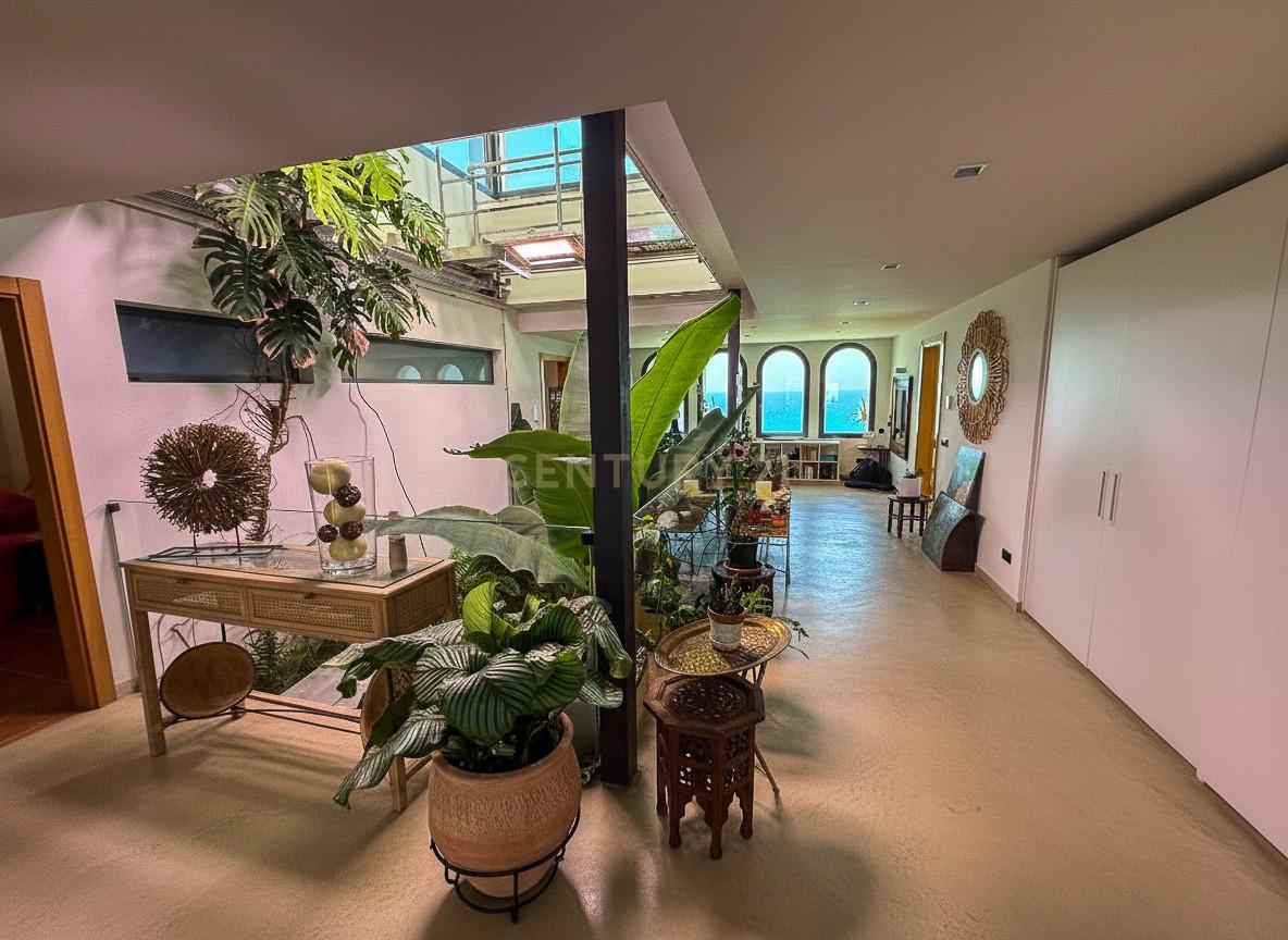 Double-height living room of Villa Can Bonita with travertine floors and arched openings framing the Mediterranean.