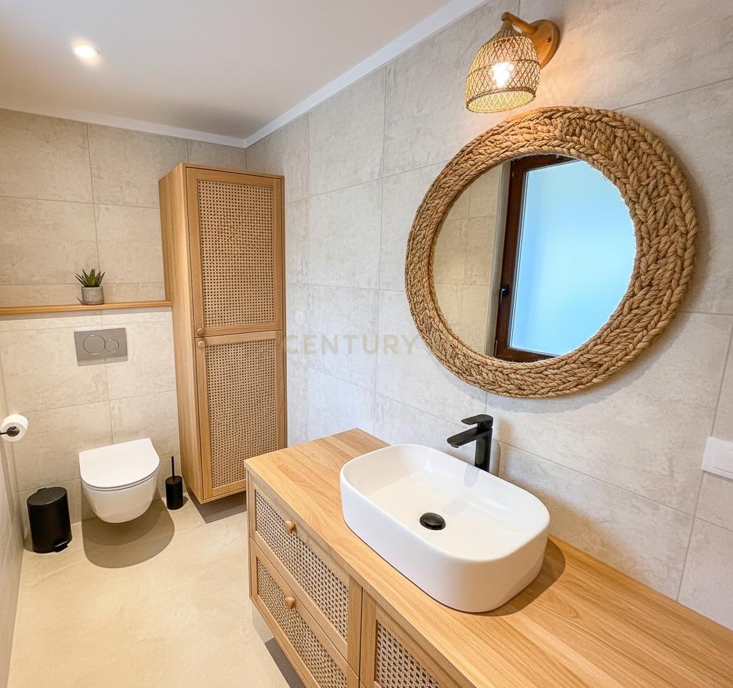 Ensuite bathroom at Villa Can Bonita with terracotta tiles, lacquered joinery and full-height sea-view window.
