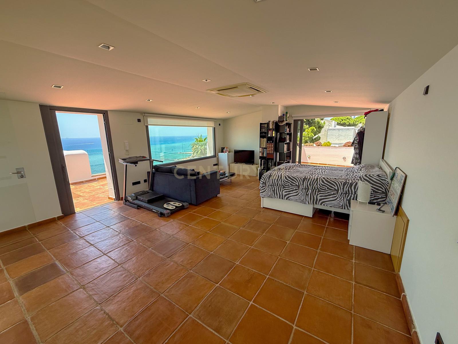 Bedroom at Villa Can Bonita with terracotta floors and private sea-view balcony opening to the horizon.